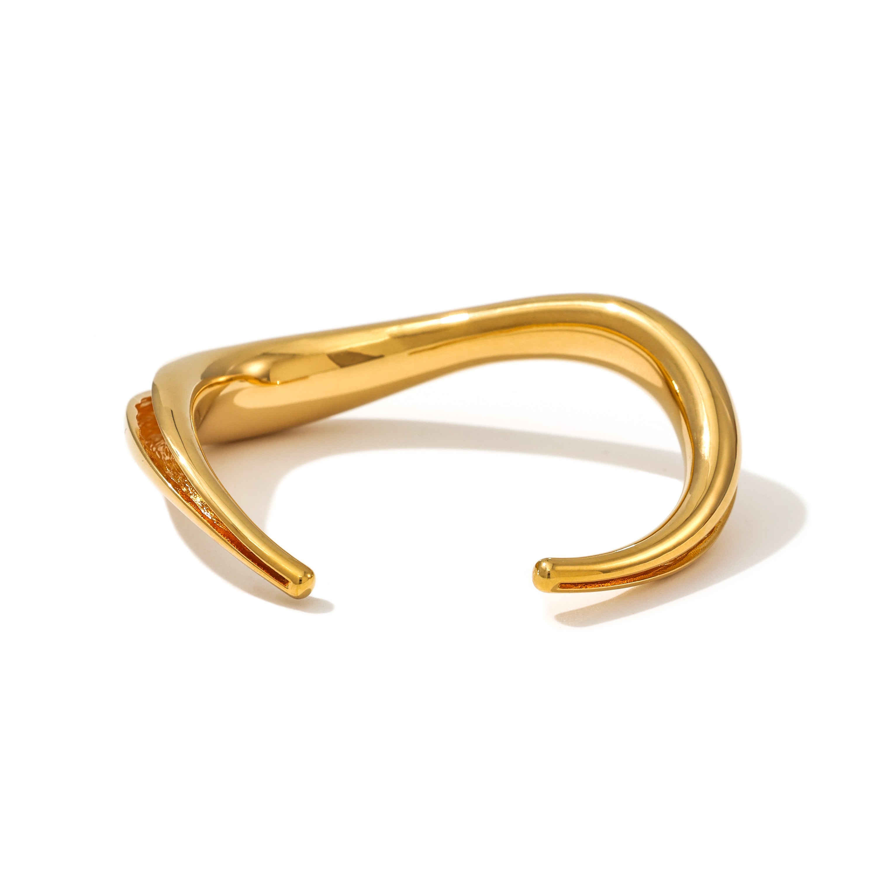 An open cuff bracelet with a smooth wave exterior and a textured inner channel. Brass plated in 24k gold or rhodium. Free U.S. shipping.