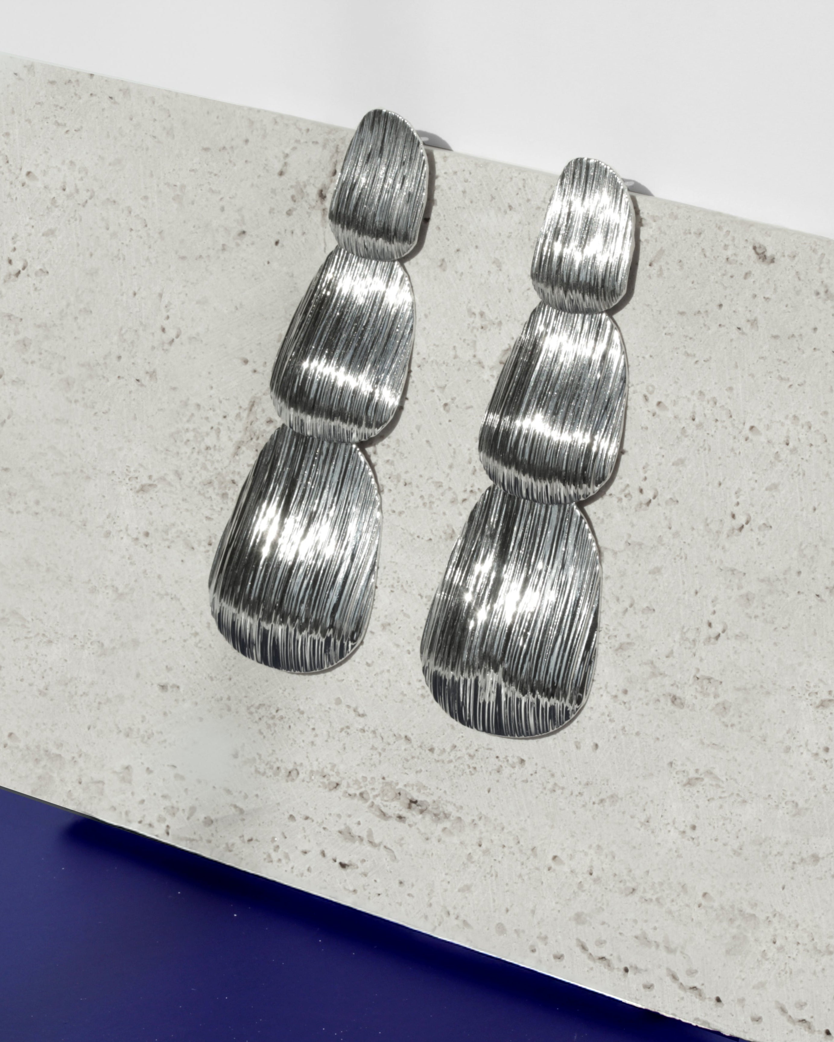 Bold layered statement earrings with textured surface and stacked form