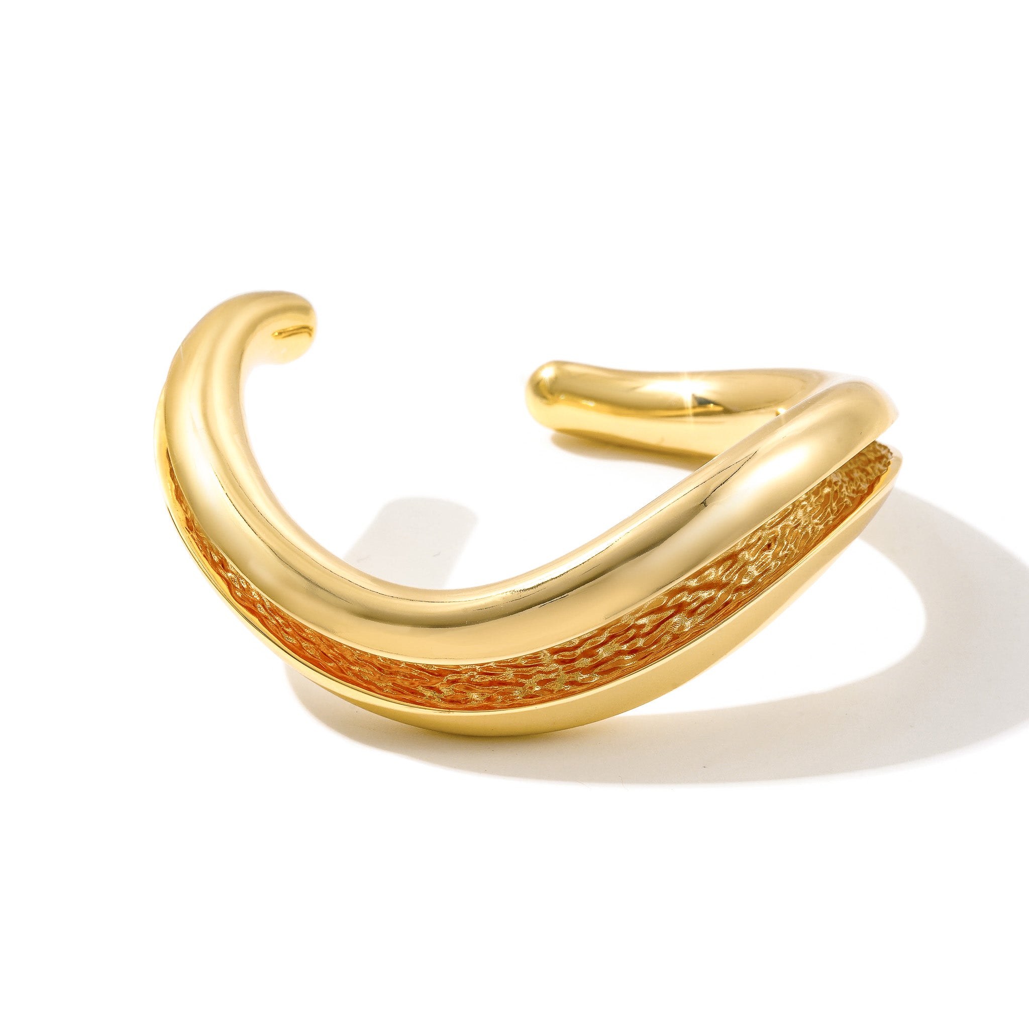 Gold Currents chunky open cuff bracelet with smooth exterior and textured inner channel, on white