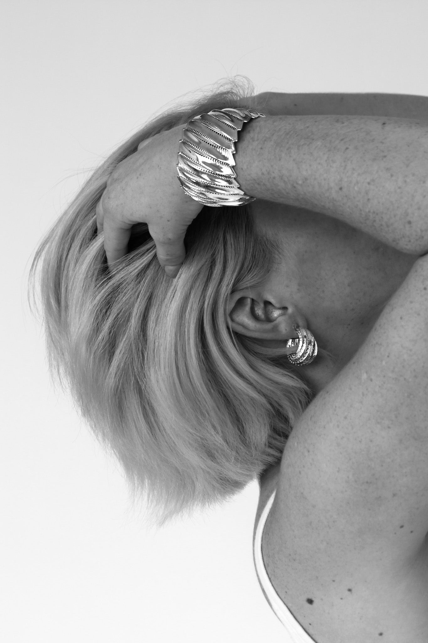 Model wearing the Flow Edgy cuff with large silver hoop earrings