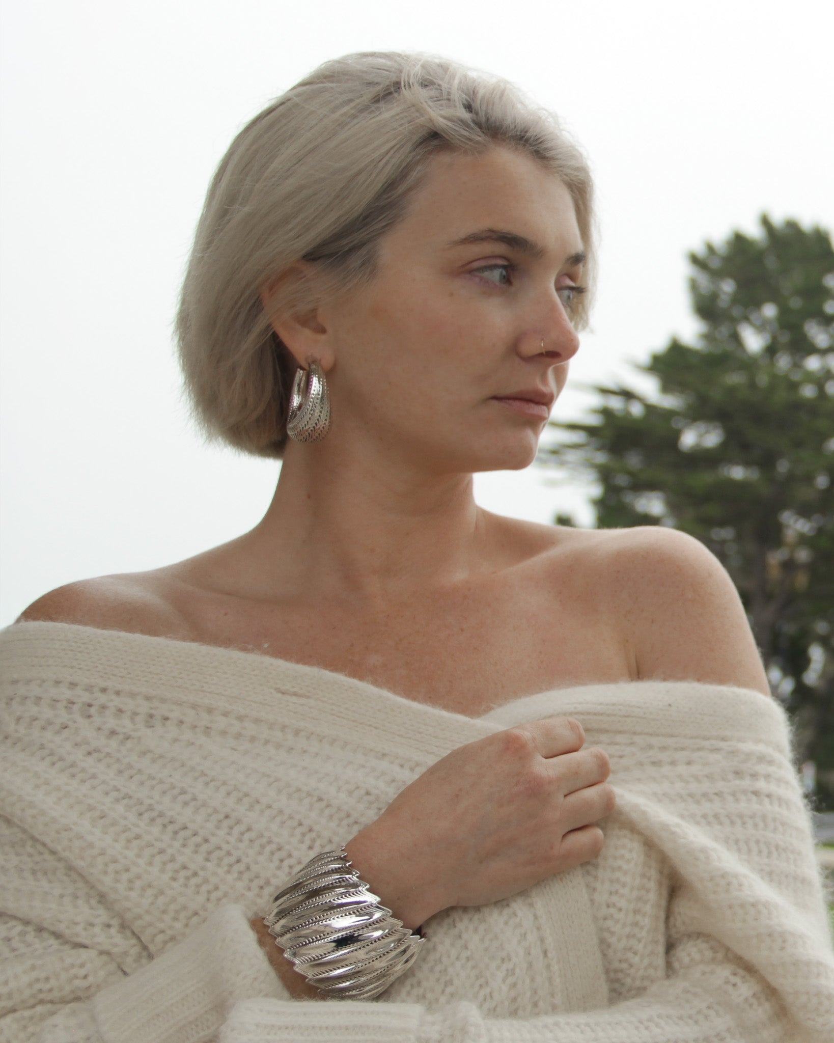 Model wearing the Flow Edgy cuff with large silver hoop earrings