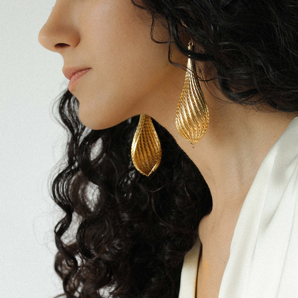 Side angle of the large gold Flow drop earrings showing the flowing ridges