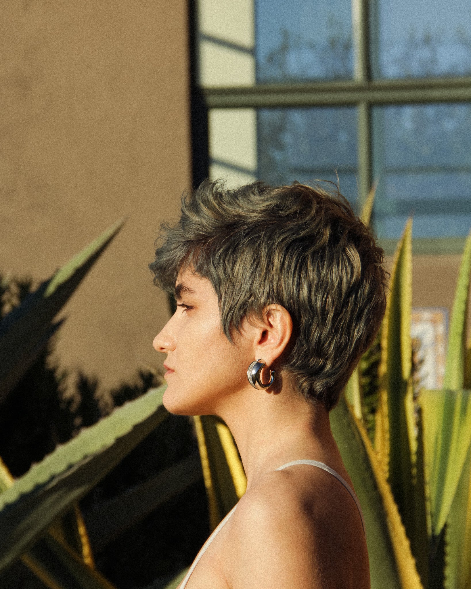 lose-up of the Currents hoop earrings on the ear, gold finish