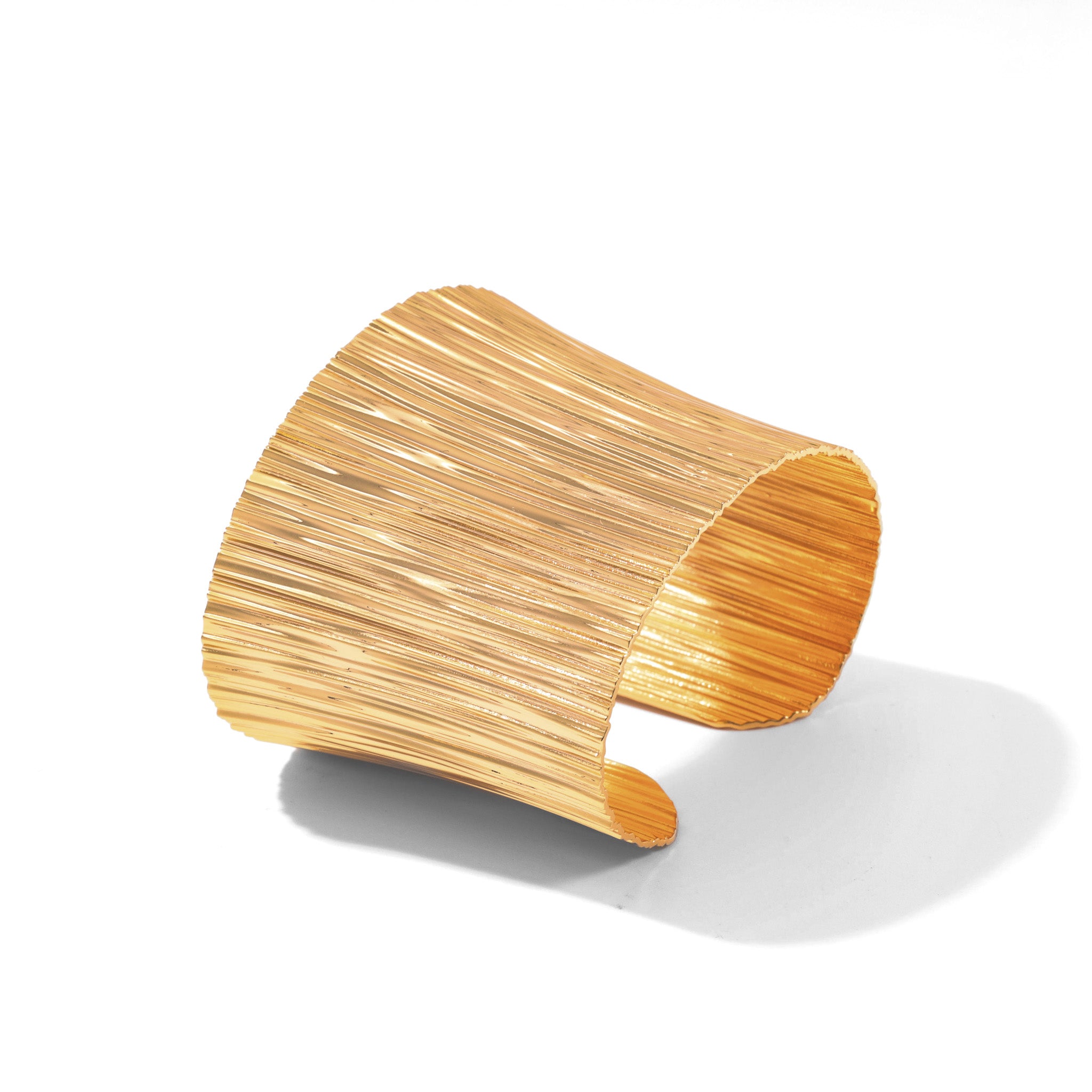 Gold Cascade cuff bracelet with a flared plunging silhouette and waterfall texture, on white