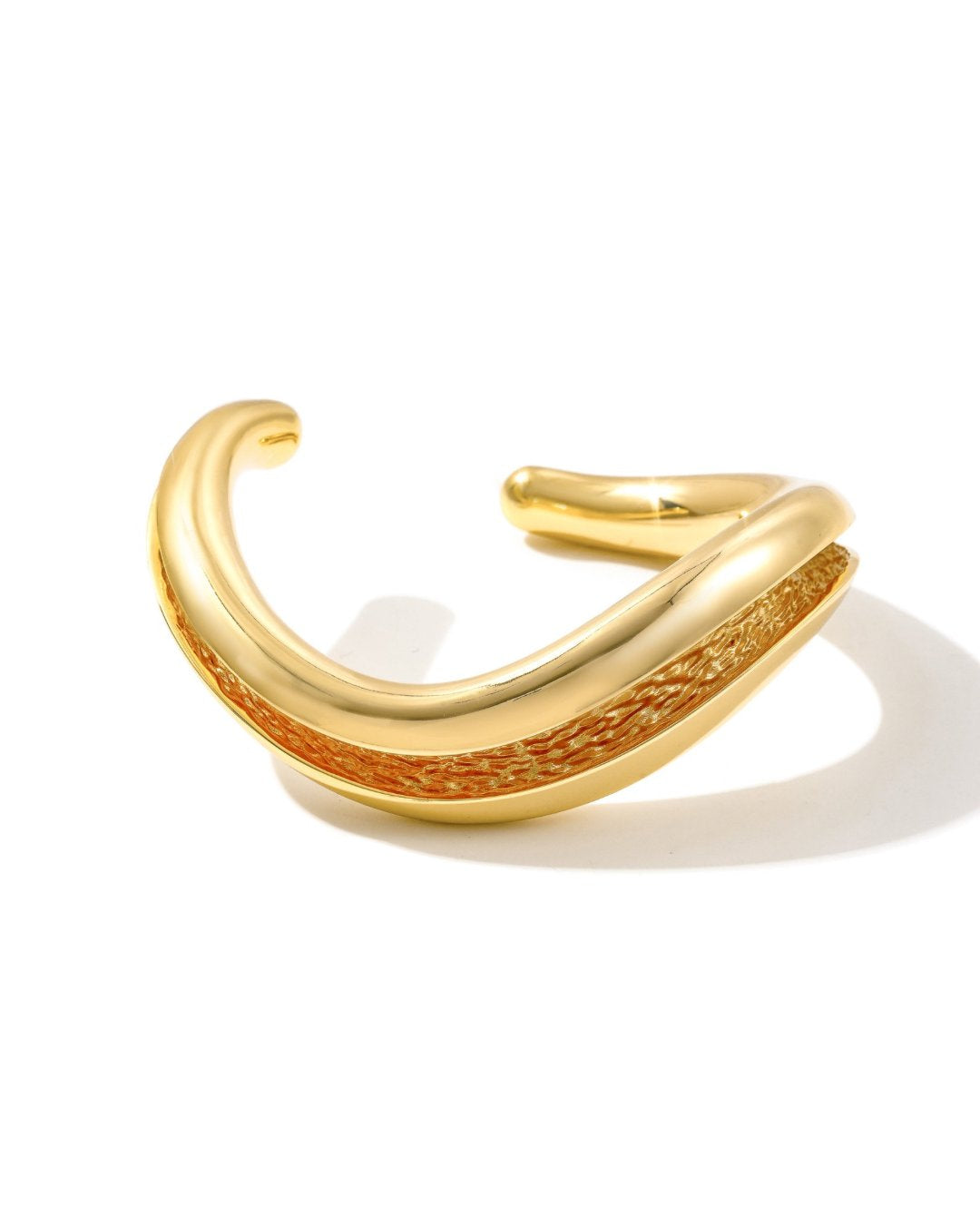 Gold Currents chunky open cuff bracelet with smooth exterior and textured inner channel, on white