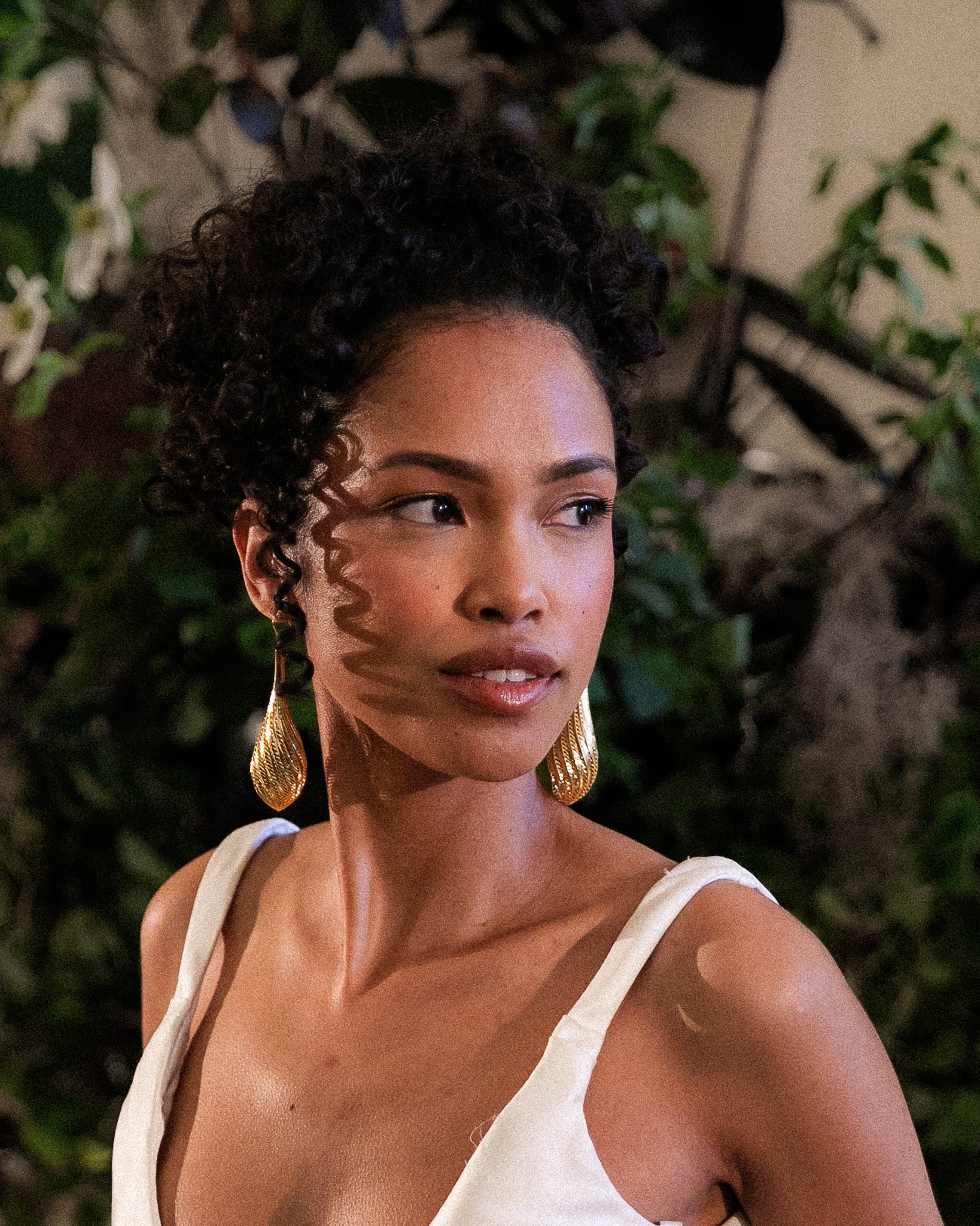 Model wearing the Flow large drop earrings in gold
