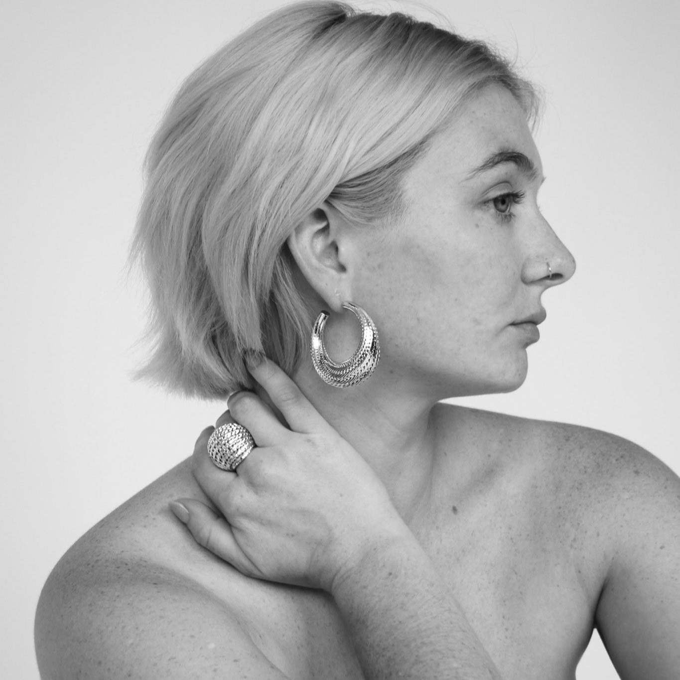 Model wearing the Flow large hoop earrings in gold
